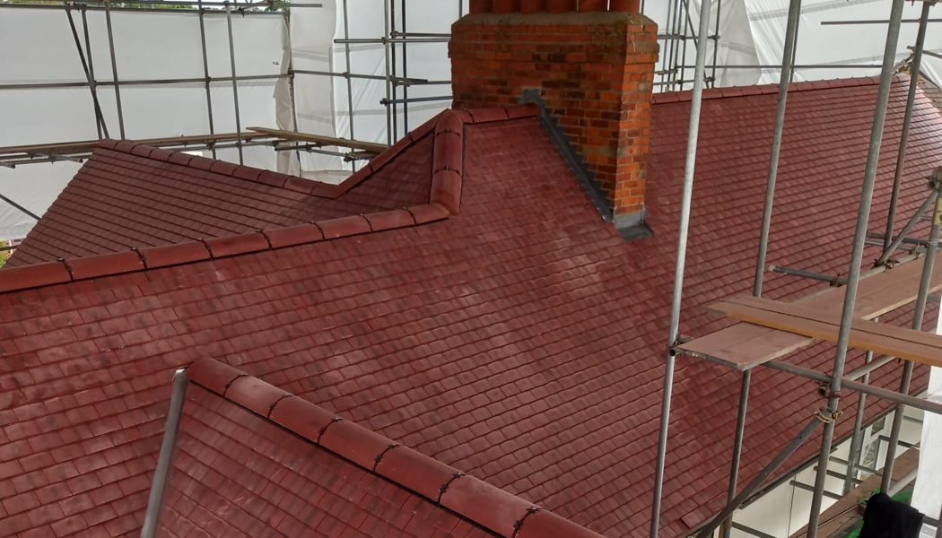 The finished Langley roof in clay plain tiles, with half-round ridge tiles and new lead flashing to the chimney
