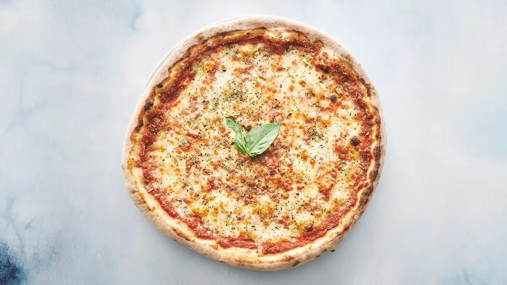 Autentisk italiensk stenovnspizza Margherita med tomatsauce, mozzarella, oregano, basilikumblade og olivenolie friskbagt på Amagerbro