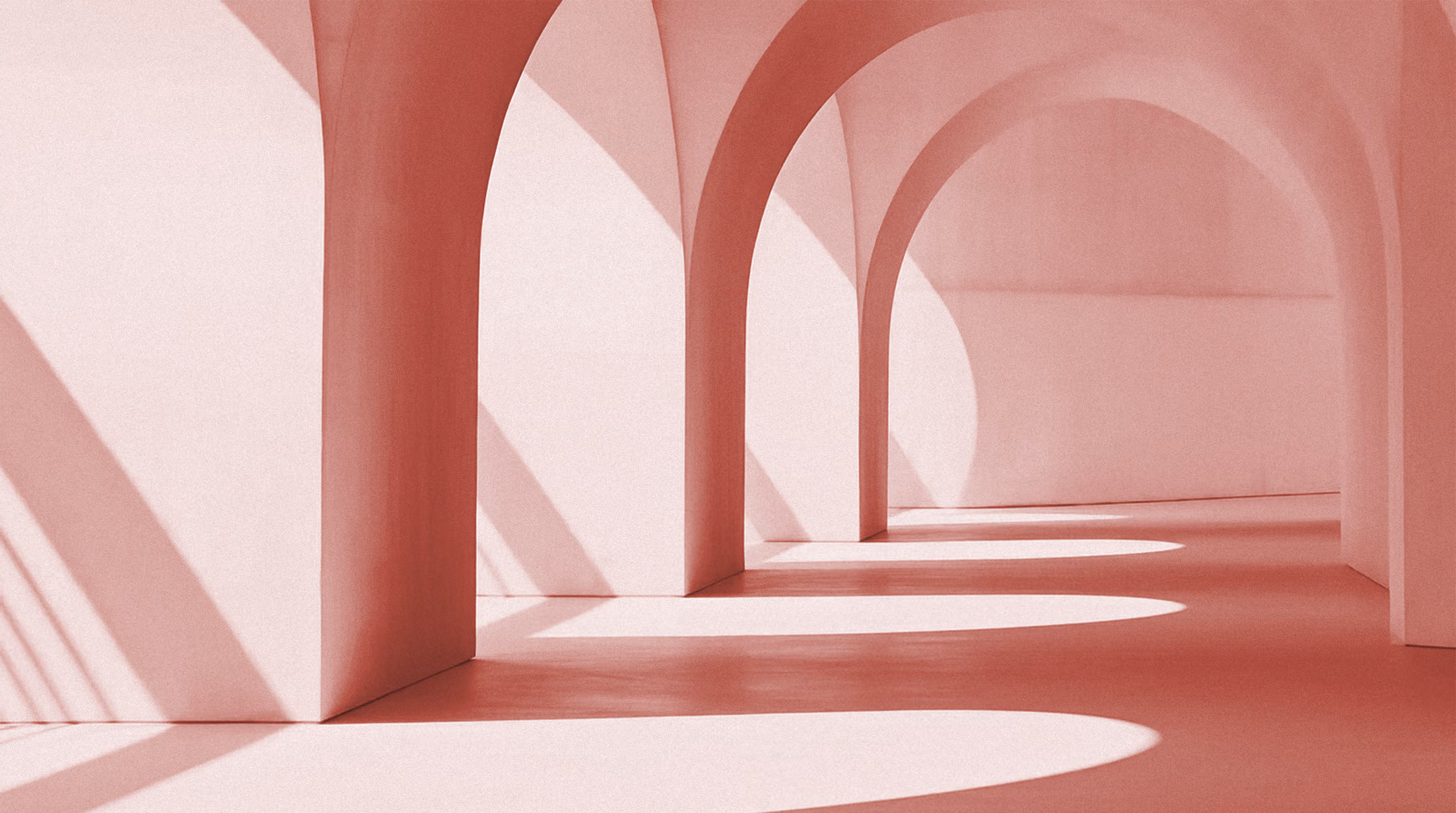 Intérieur d'un couloir avec des arches arrondies en mur rose clair, éclairé par la lumière du soleil créant des ombres incurvées au sol.