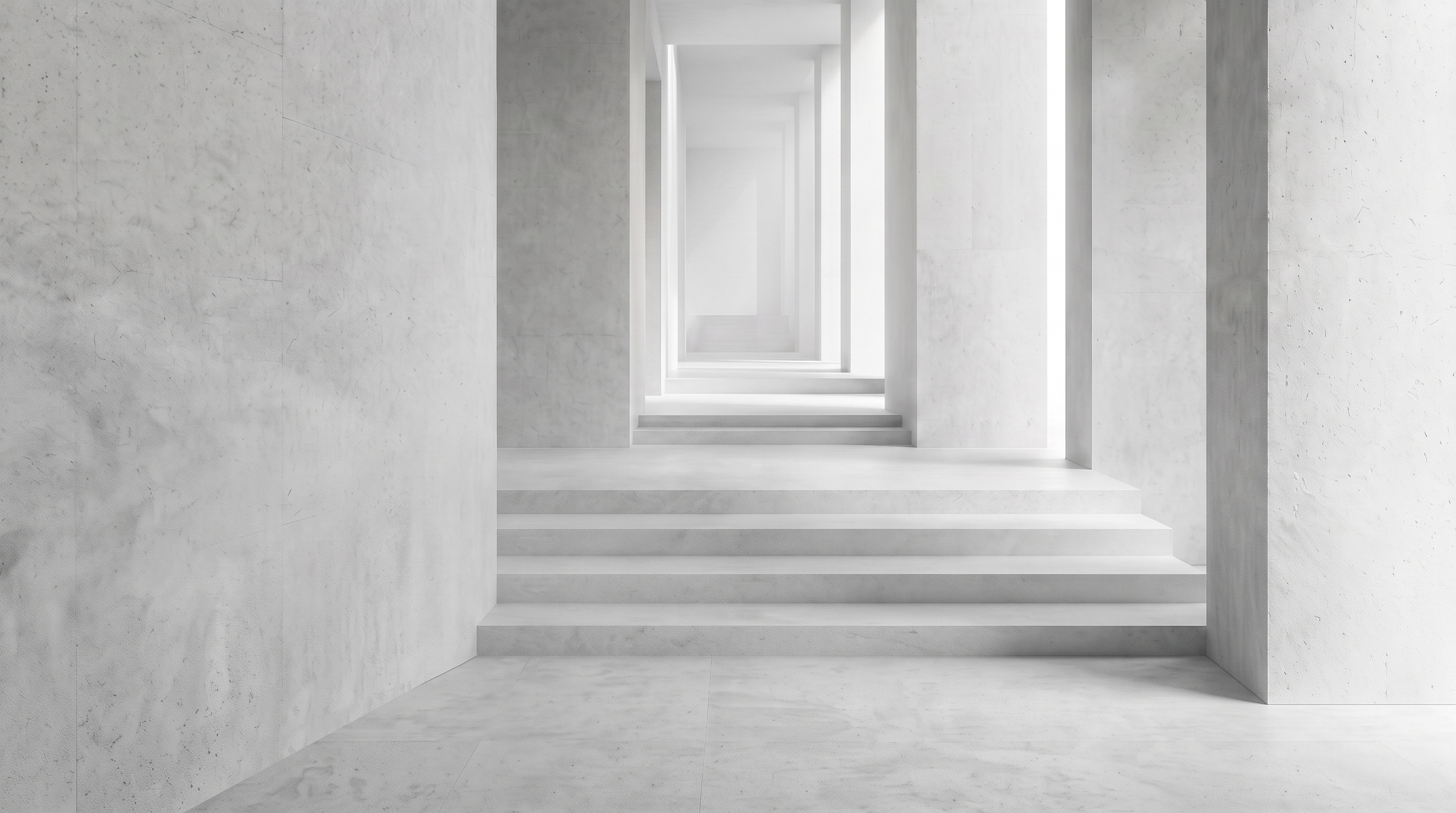 Un long couloir minimaliste en béton blanc avec des escaliers répétés créant une perspective profonde et symétrique.