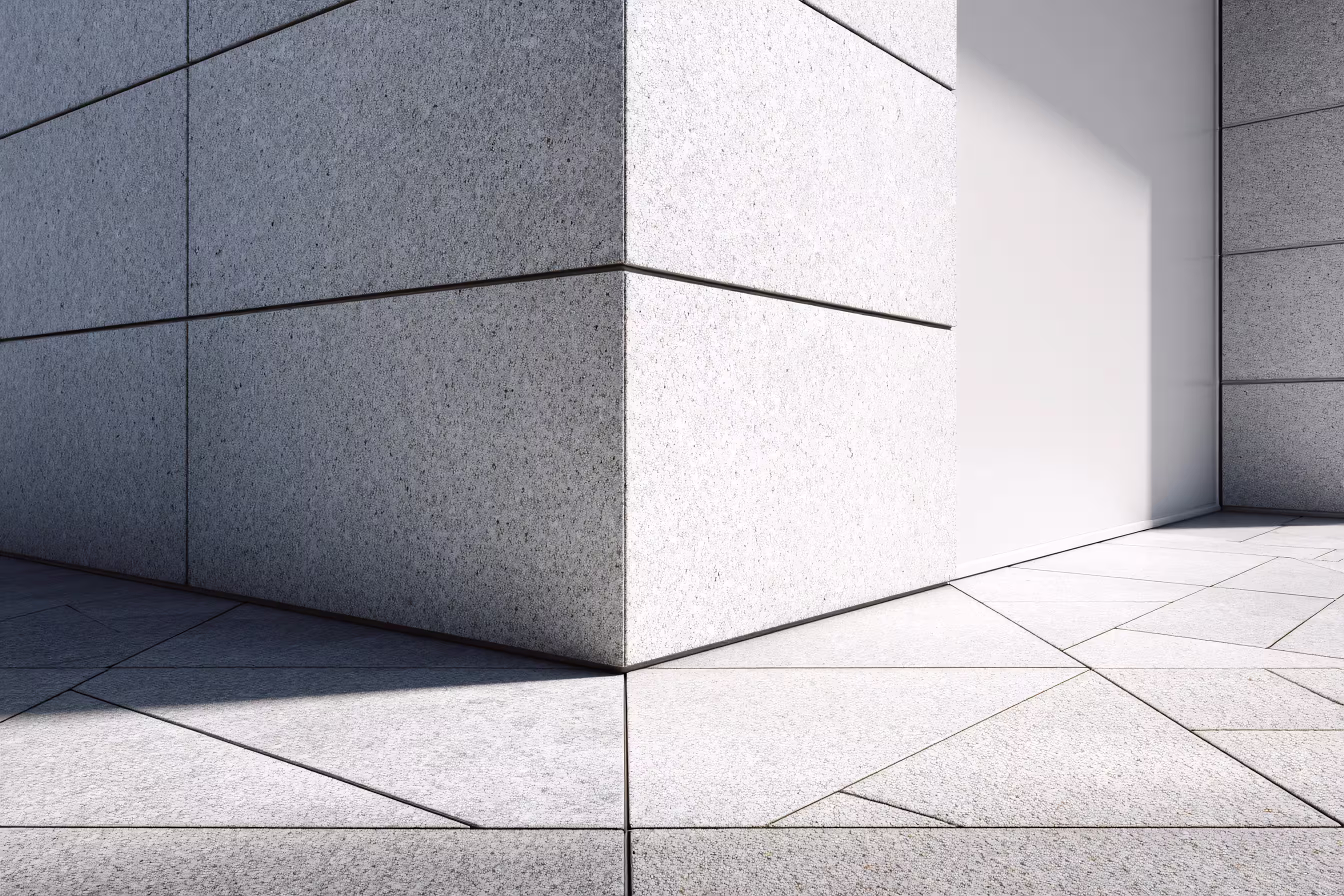 Ecke eines modernen Gebäudes aus grauem Granit mit Schatten und geometrischem Pflasterboden.