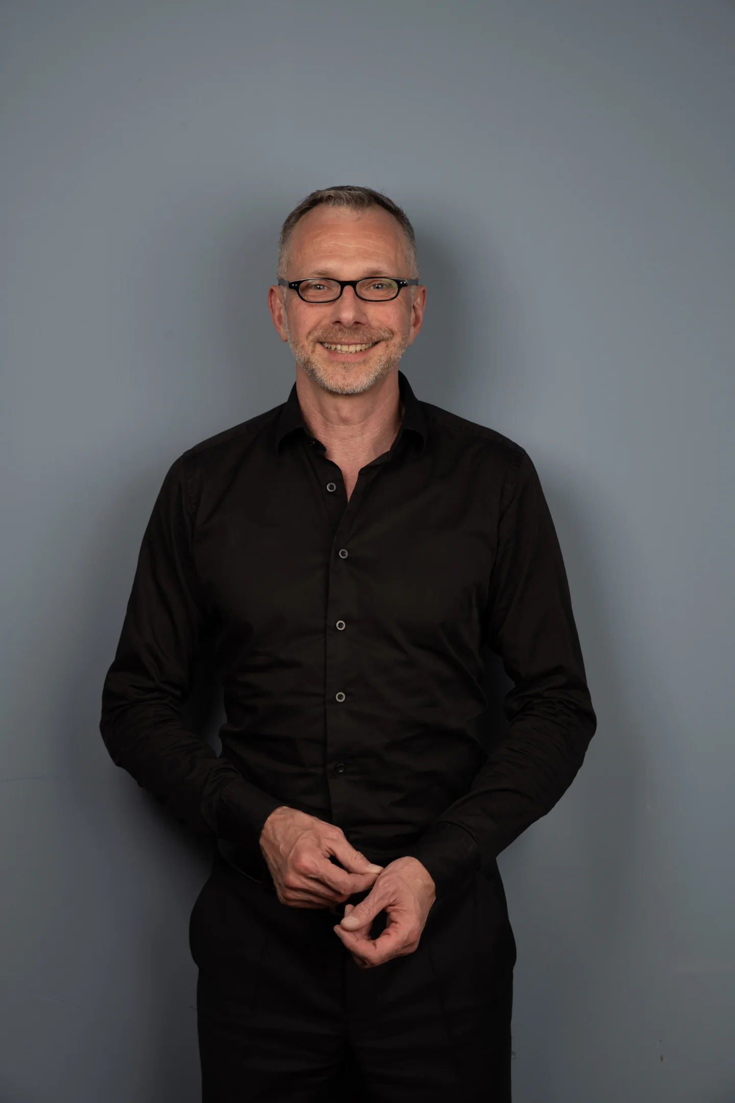 Porträt von Holger Kampe vor grauem Hintergrund.