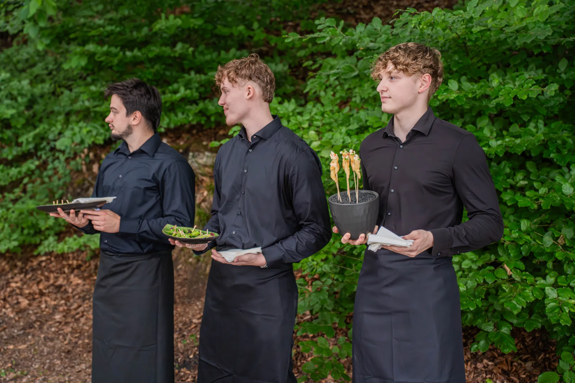 Service staff carrying flying dinner plates in the forest