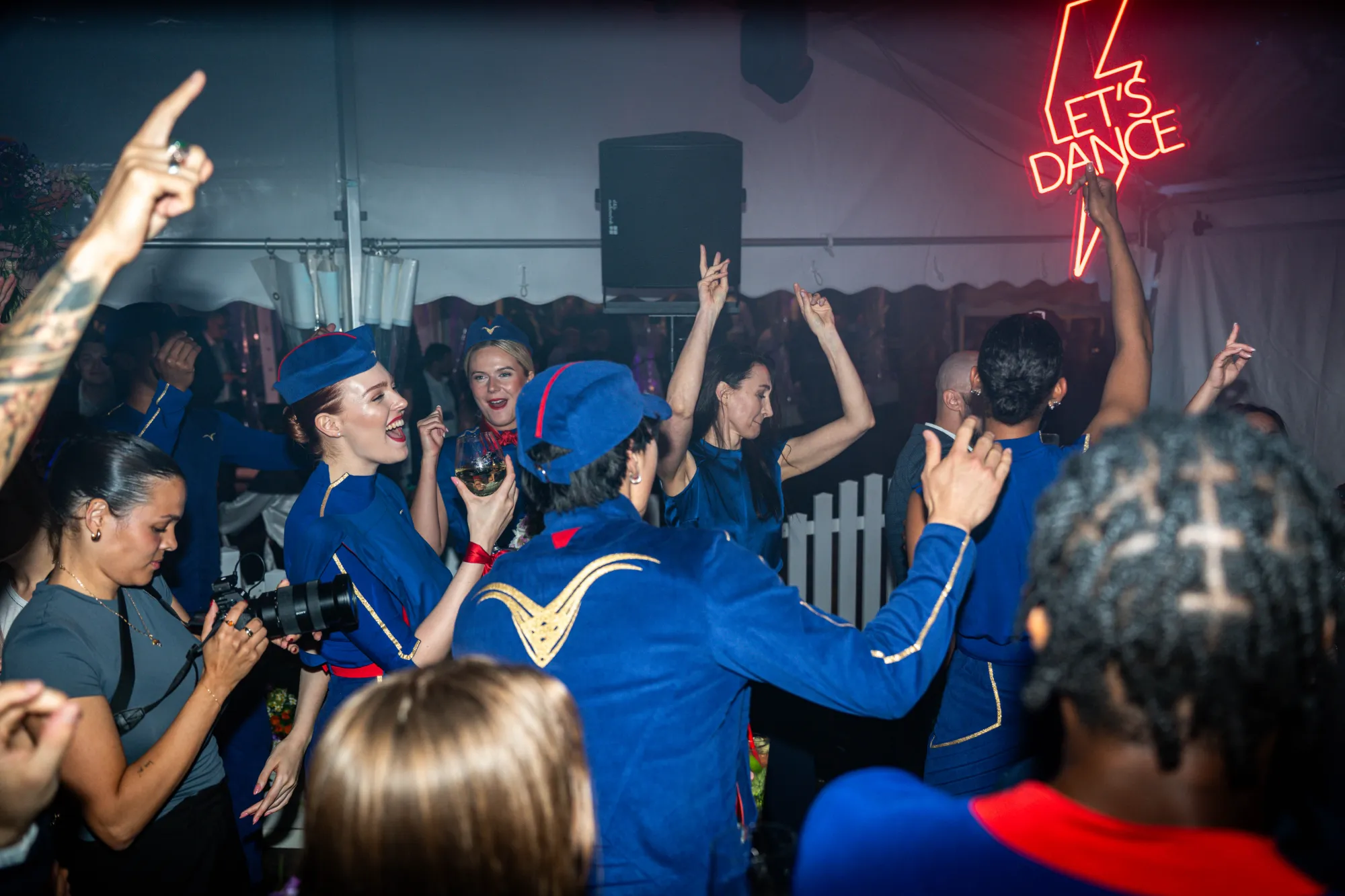 Guests and dancers in blue uniforms celebrating on the dance floor