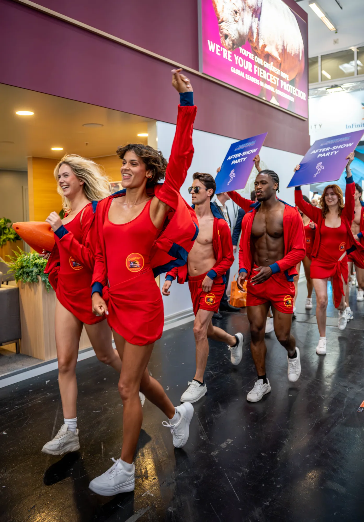 Walk act in red lifeguard outfits inviting trade fair visitors to the after-show party