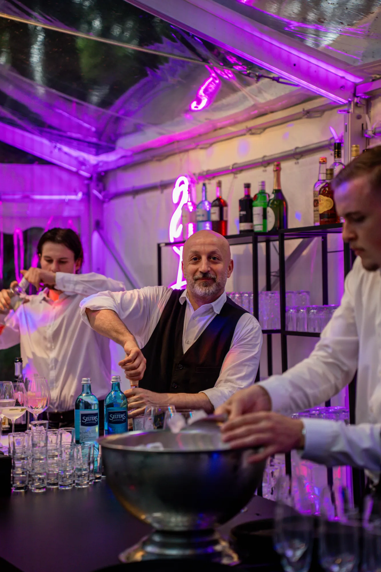 Bartenders at the cocktail bar in the illuminated tent