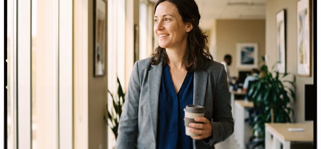 Femme d'affaires souriante tenant un gobelet de café dans un bureau