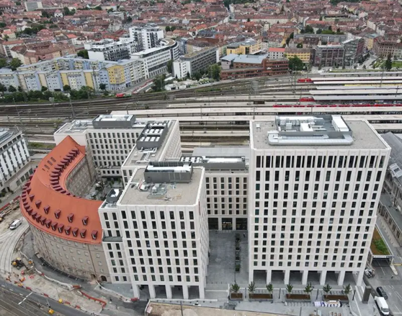 Luftaufnahme von modernen mehrstöckigen Gebäuden neben Bahngleisen und einem städtischen Wohngebiet.