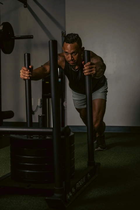 **Alt text:** Athlete pushing a weighted sled during a HYROX training class at a fitness gym in Bakersfield, CA.