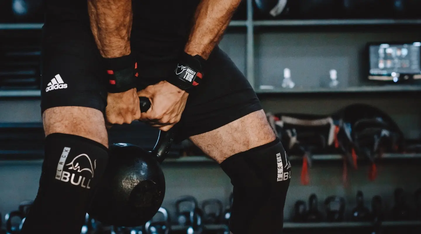 **Alt text:** Athlete lifting a kettlebell during a CrossFit strength training workout at a gym in Bakersfield, CA.