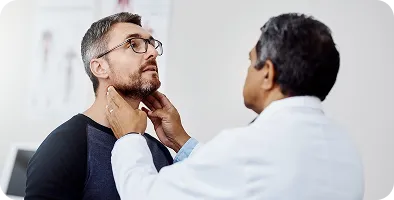 Doctor examining a male patient's neck during a medical checkup in a clinical setting.