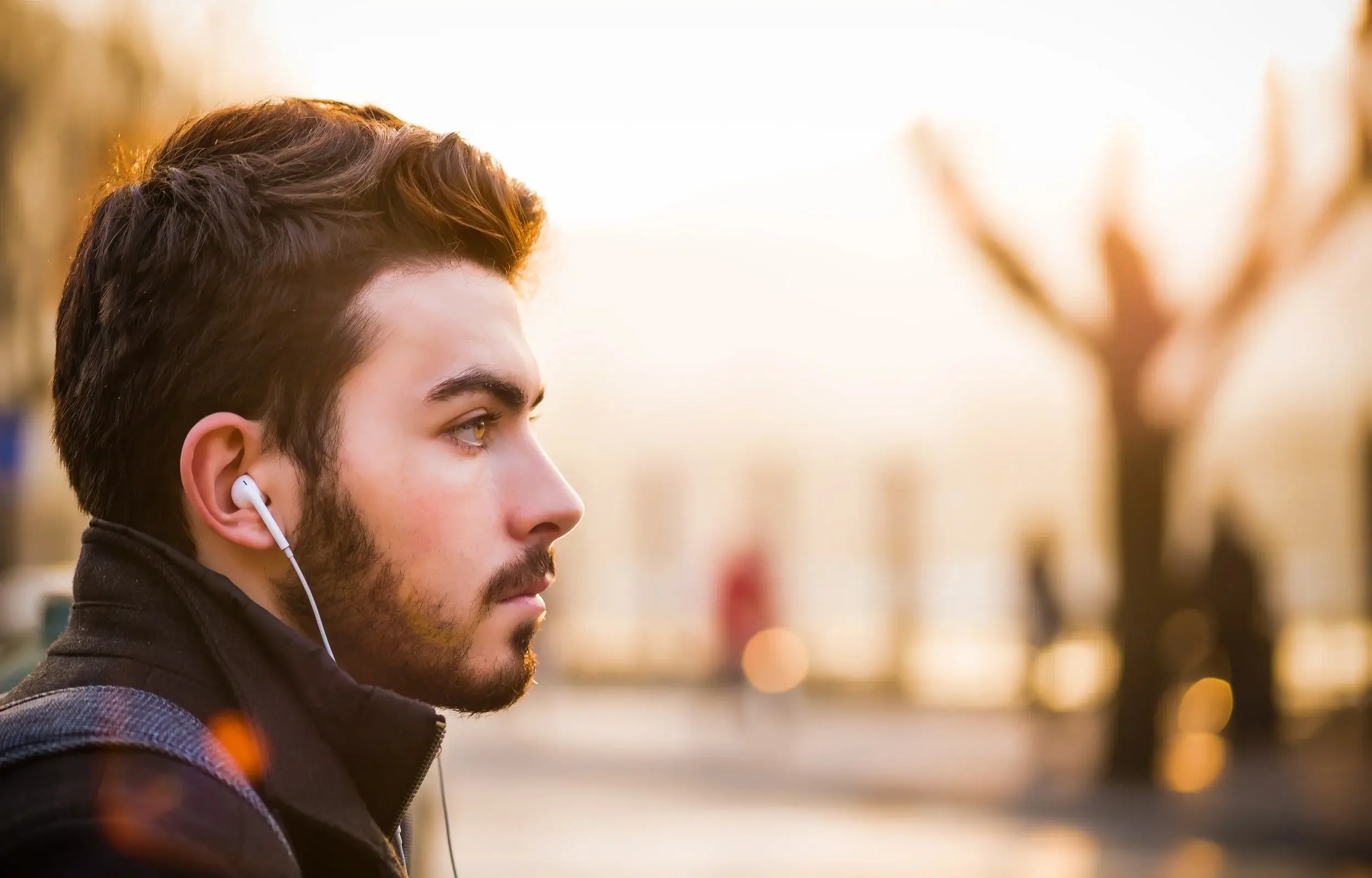 Man wearing earphones looking into the distance on a quiet street