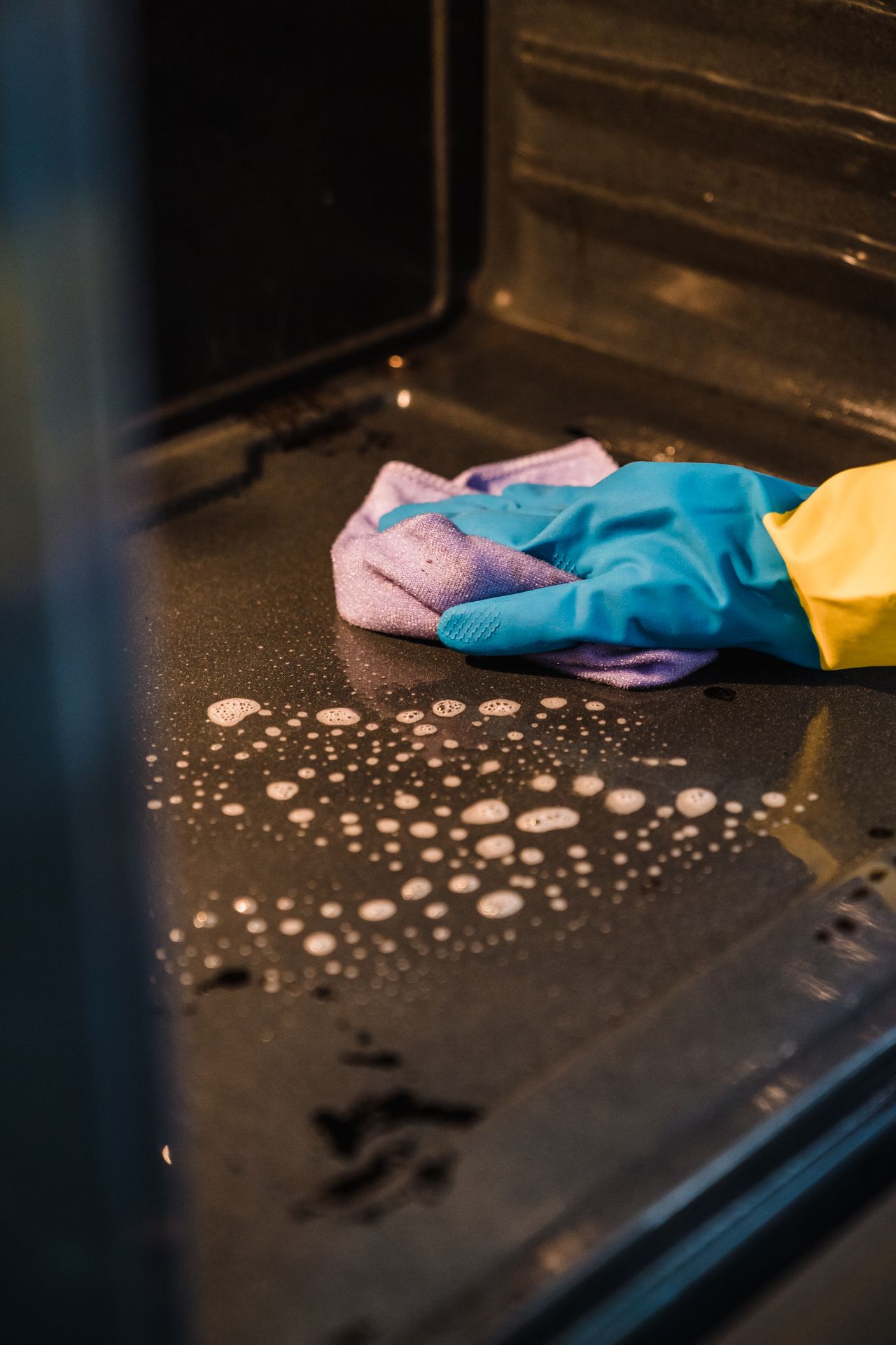 A gloved hand cleaning an oven interior during a Marina Gleam Deep Cleaning visit