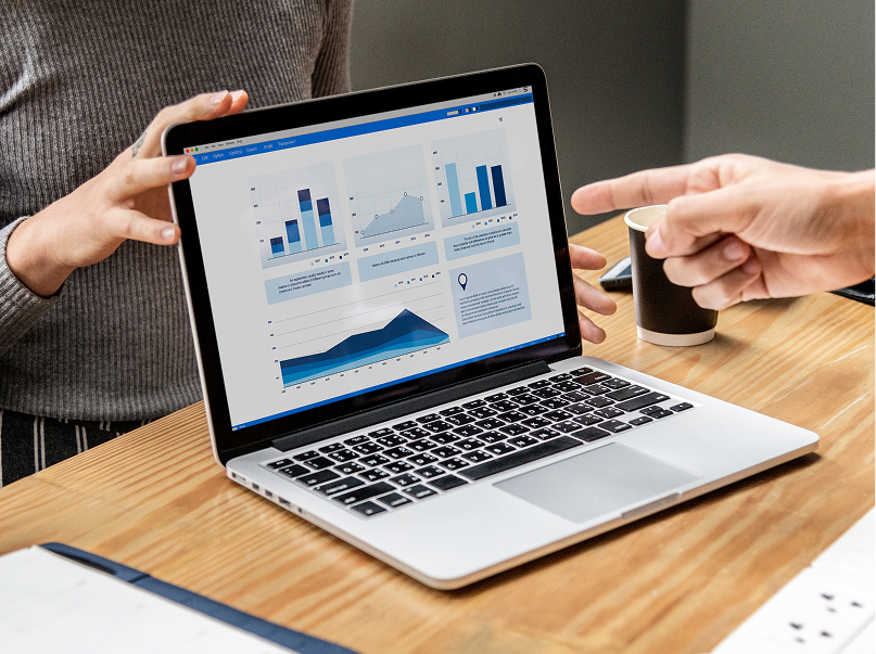 Two colleagues reviewing data analytics charts on a laptop screen using Motodisk software on a wooden office desk.