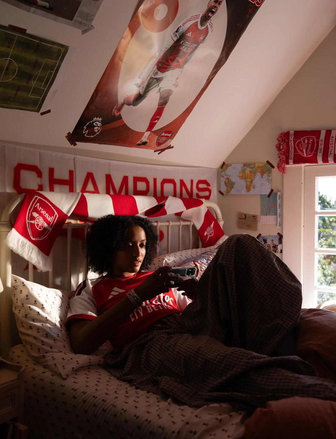 Girl relaxing in her Arsenal-themed room.