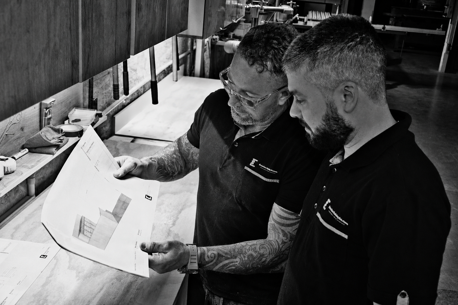 Two Evolution team members reviewing joinery drawings in the Auckland workshop