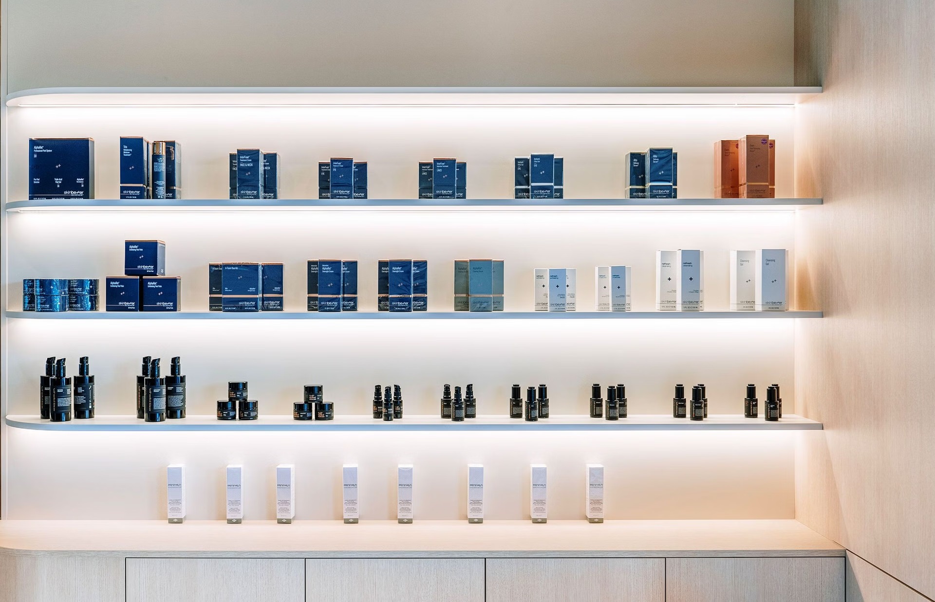 Illuminated product-display shelving integrated into timber cabinetry at A+ Cosmetic Clinic