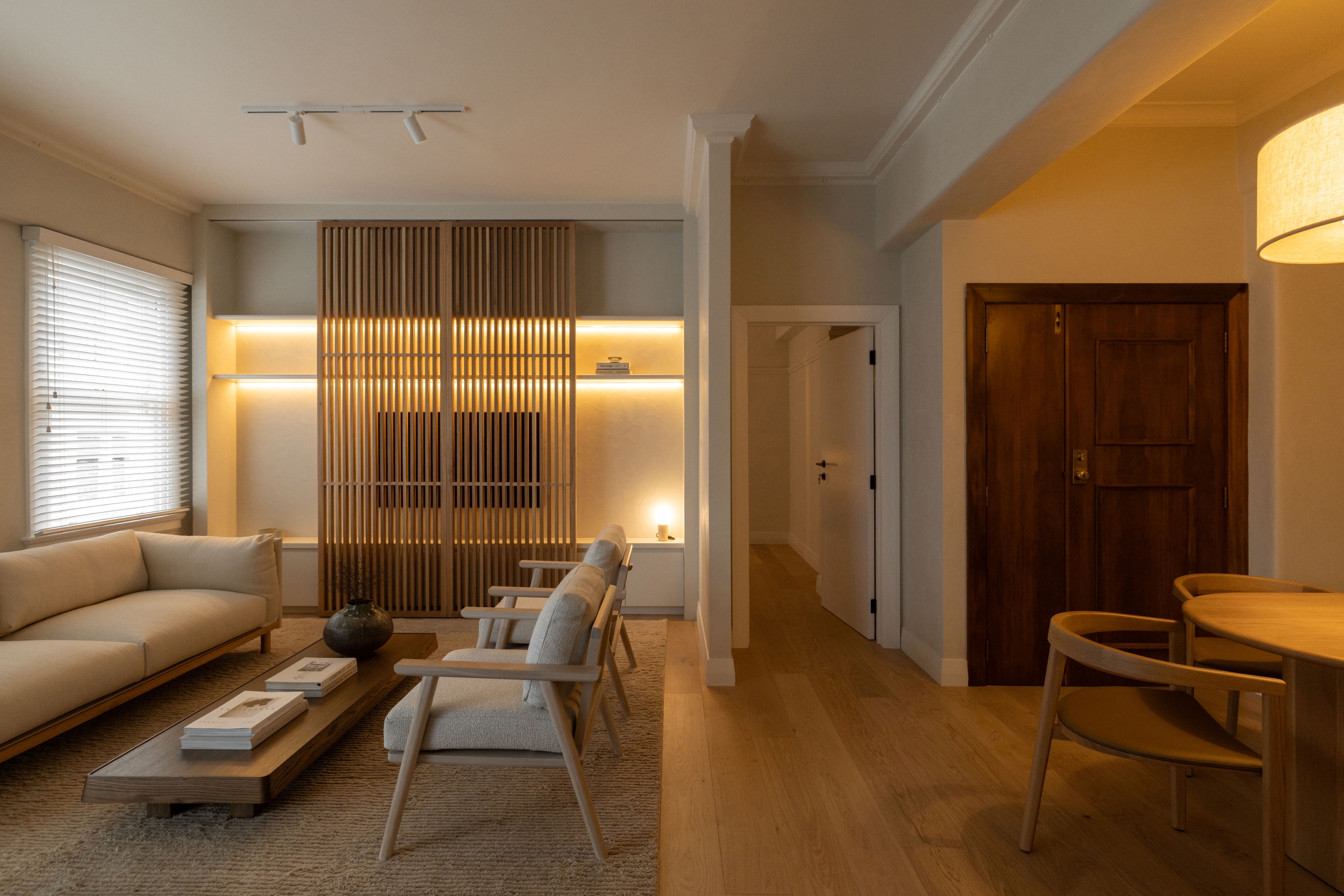 Wide view across Westminster Court living and dining spaces with illuminated timber screen