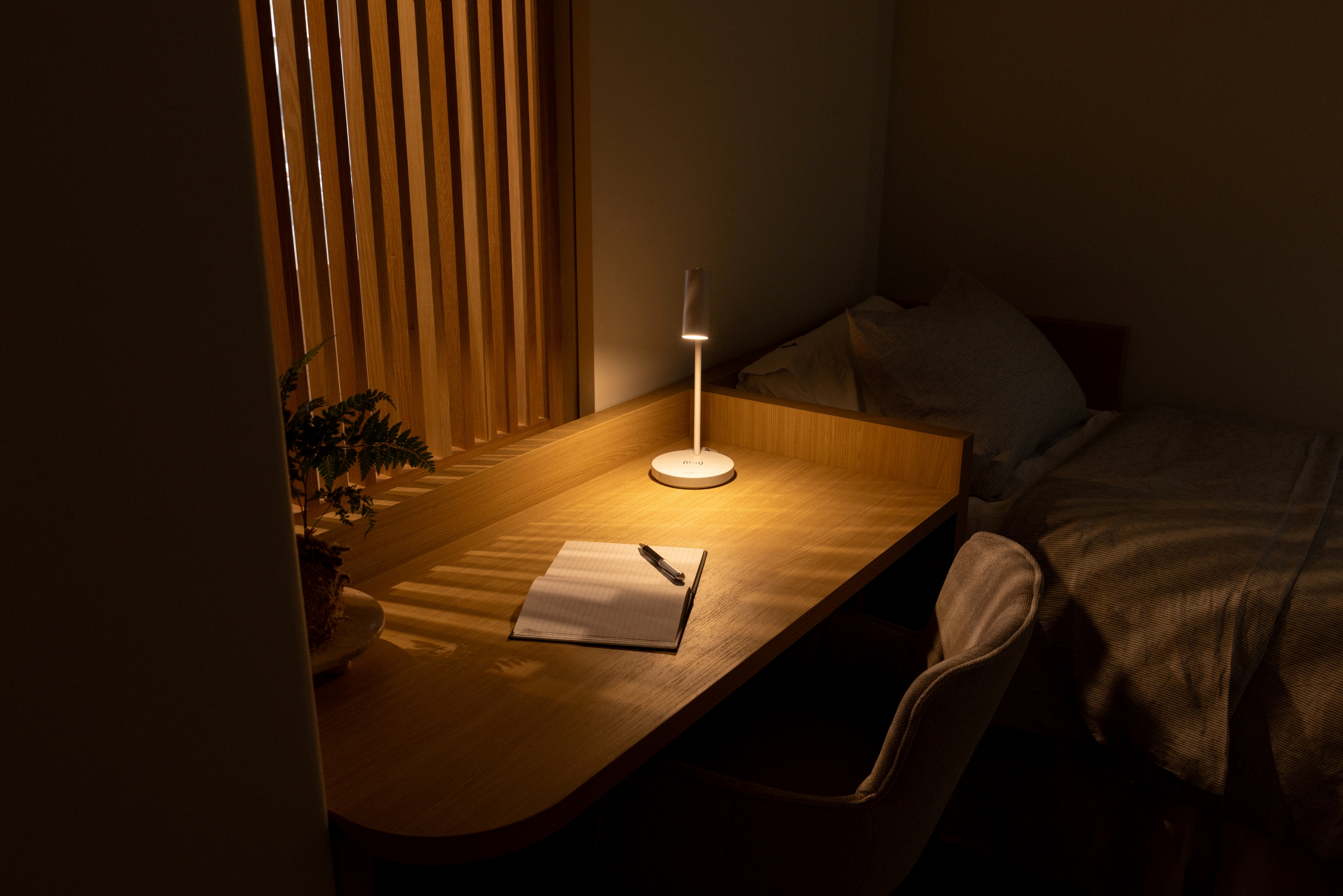 Integrated timber desk and bedside joinery at Westminster Court, lit through the timber screen