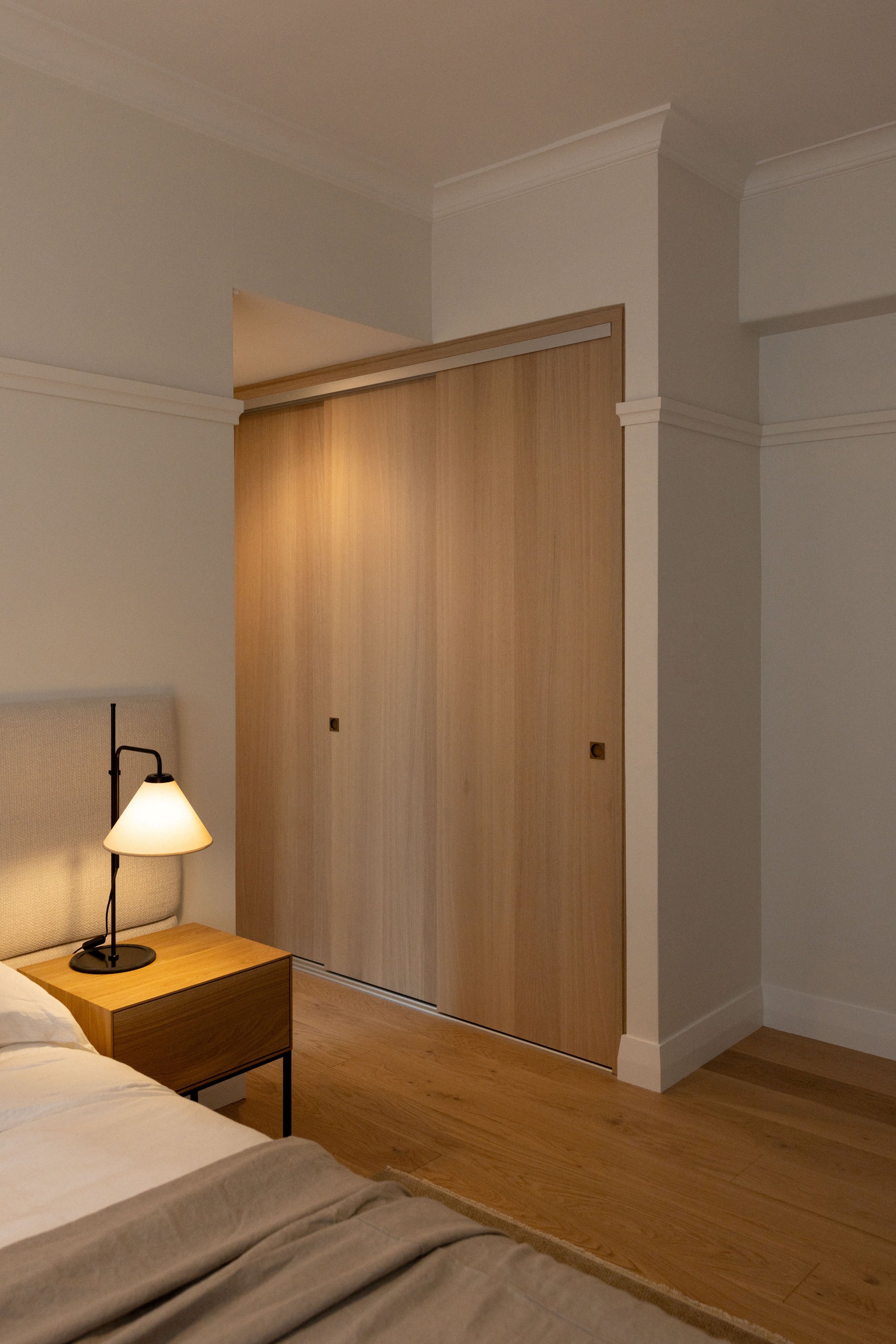 Bedroom at Westminster Court with full-height timber sliding panels and integrated bedside cabinetry