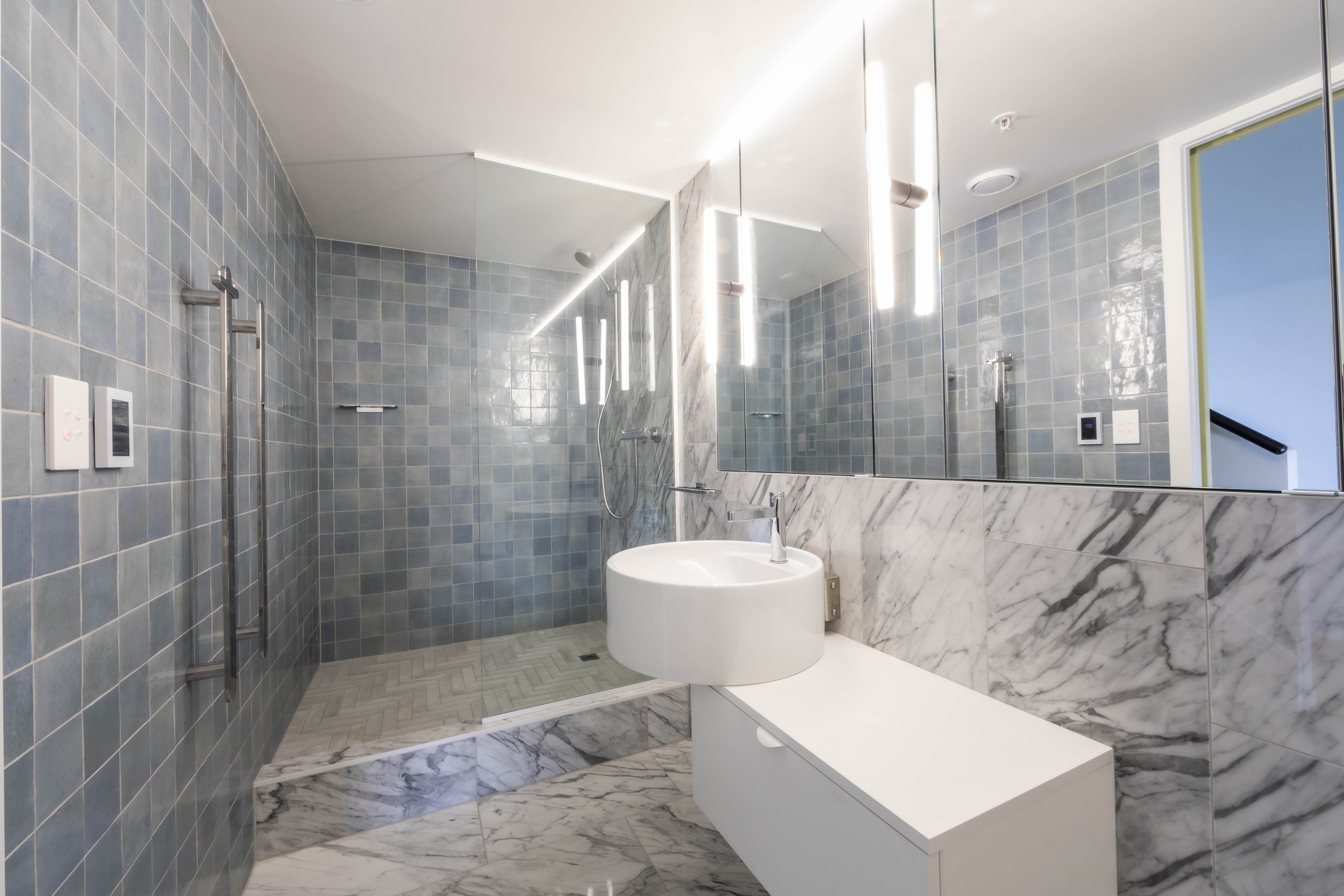 Bathroom with custom white vanity, marble wall lining and blue tiles at George Court Apartment
