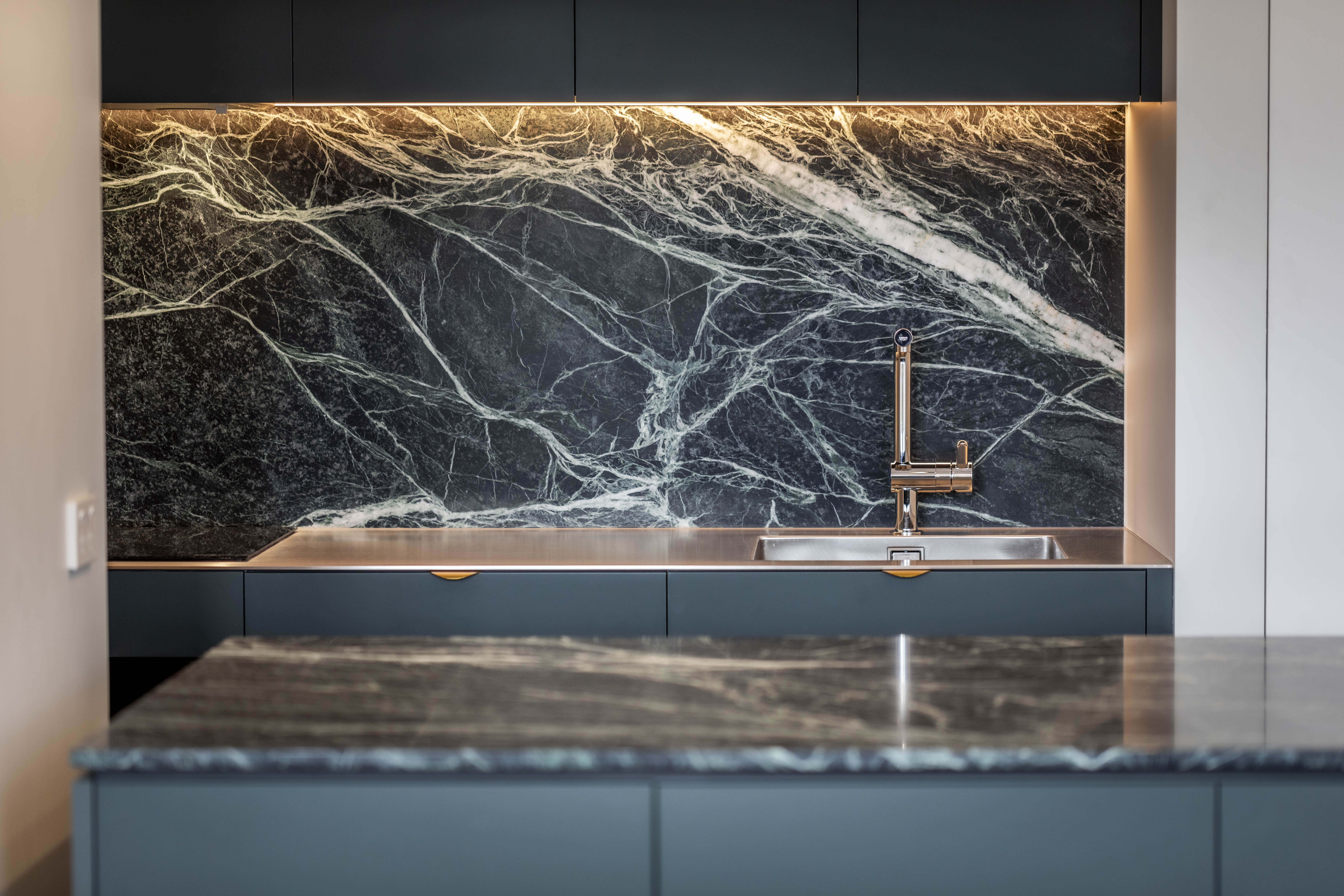Kitchen sink, dark stone splashback and custom cabinetry at George Court Apartment