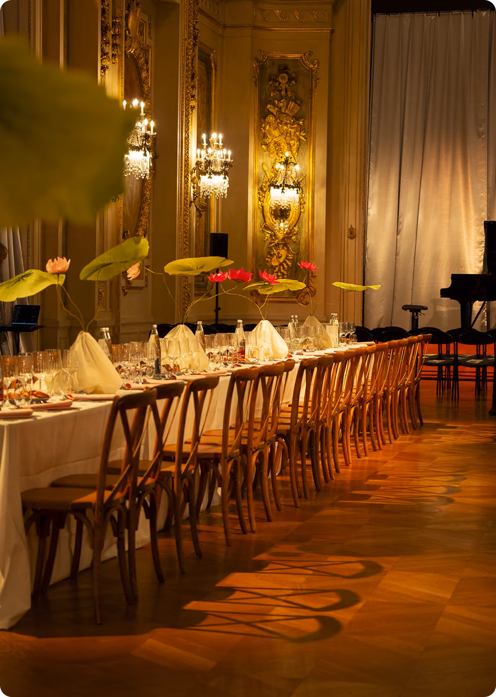 Table élégamment dressée dans une salle luxueuse avec chaises en bois et décorations florales vertes et rouges.