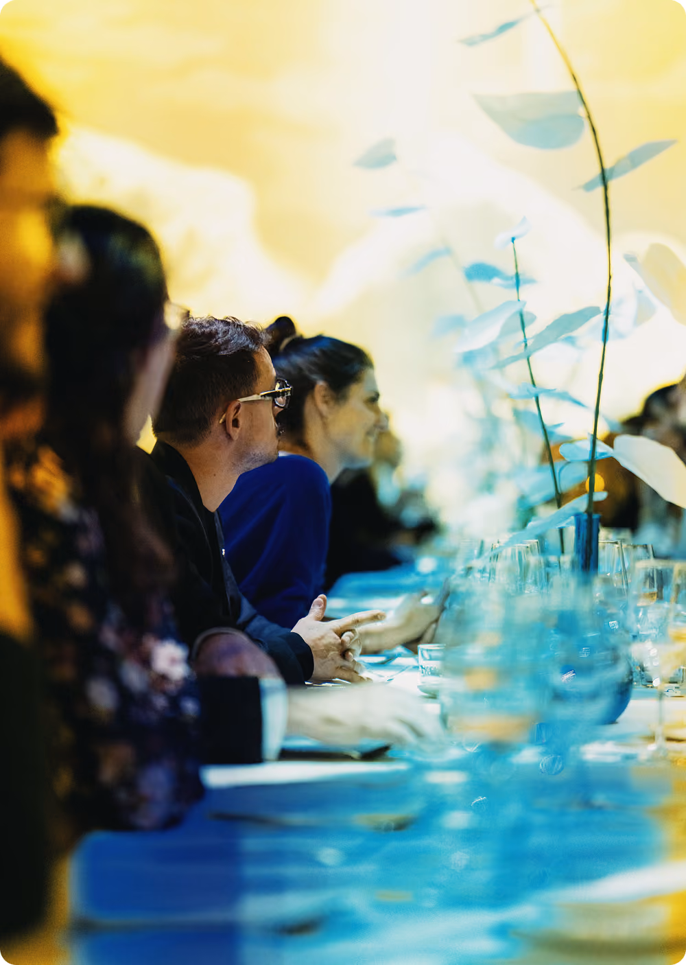 Personnes assises à une table élégamment dressée avec des verres et une décoration florale.