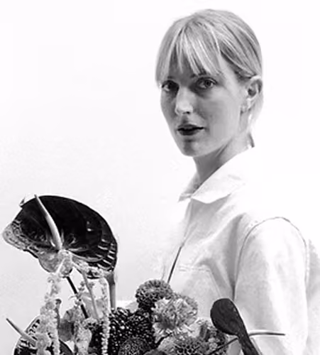 Portrait en noir et blanc d'une femme blonde tenant un bouquet de fleurs variées.