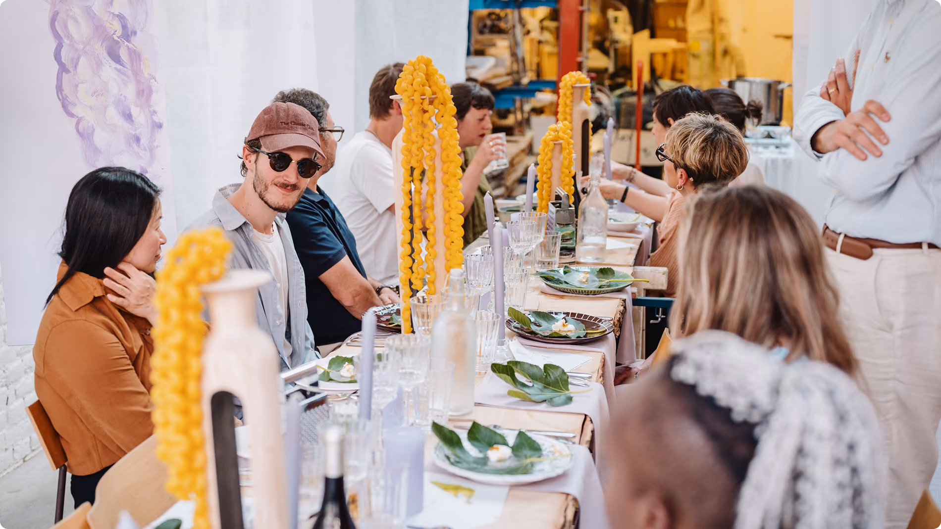 Groupe de personnes assises autour d'une table décorée avec des feuilles vertes et bougies.
