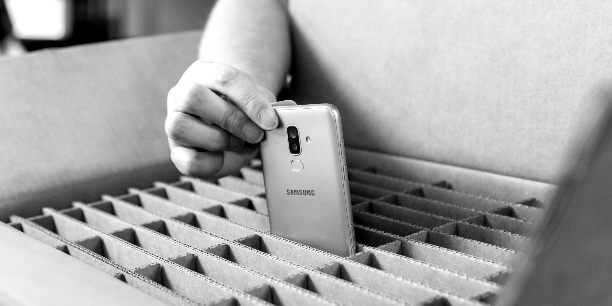A Samsung smartphone being placed into a protective foam divider for transport.