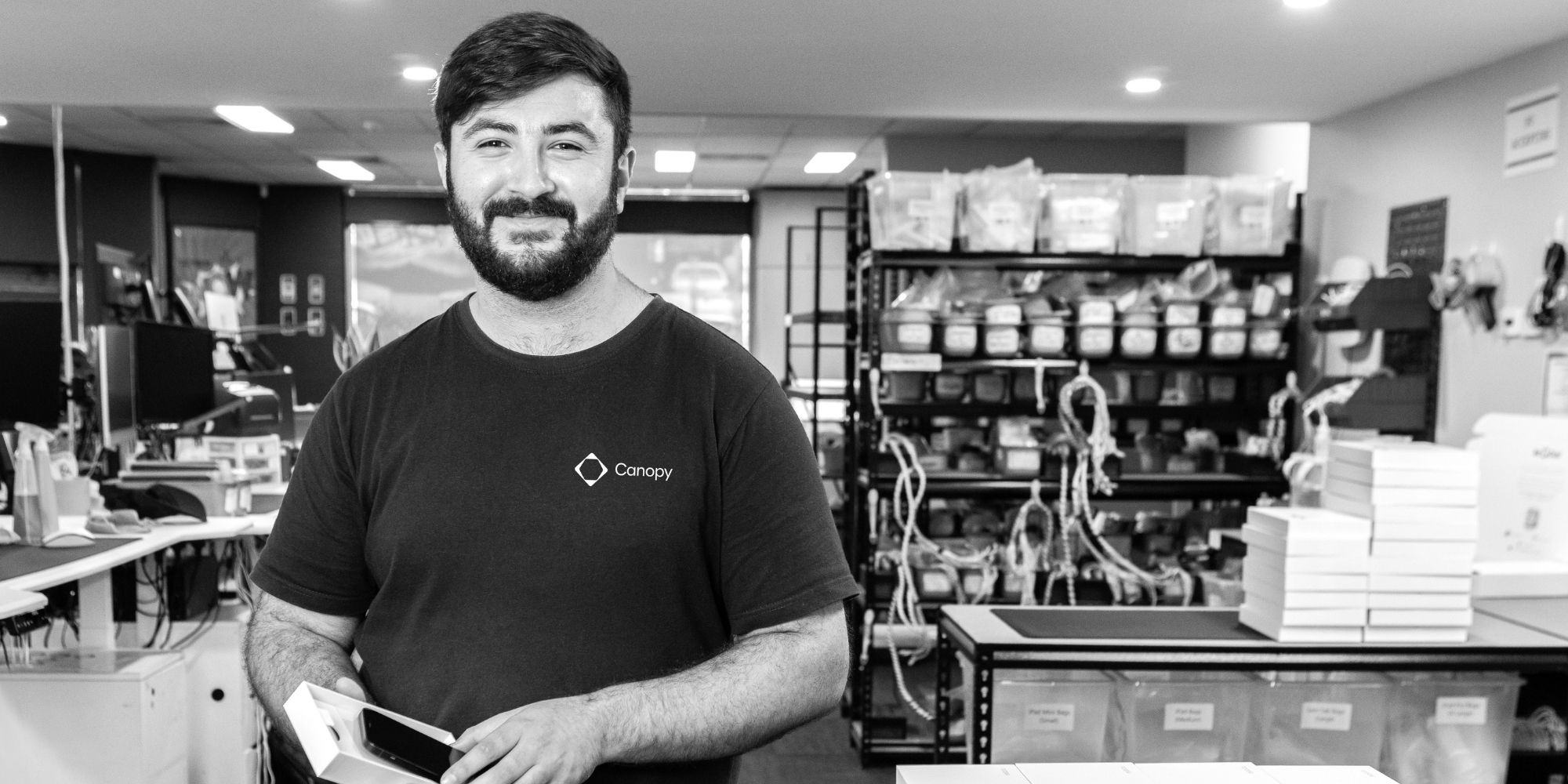 Canopy team member holding a smartphone in the device processing area.
