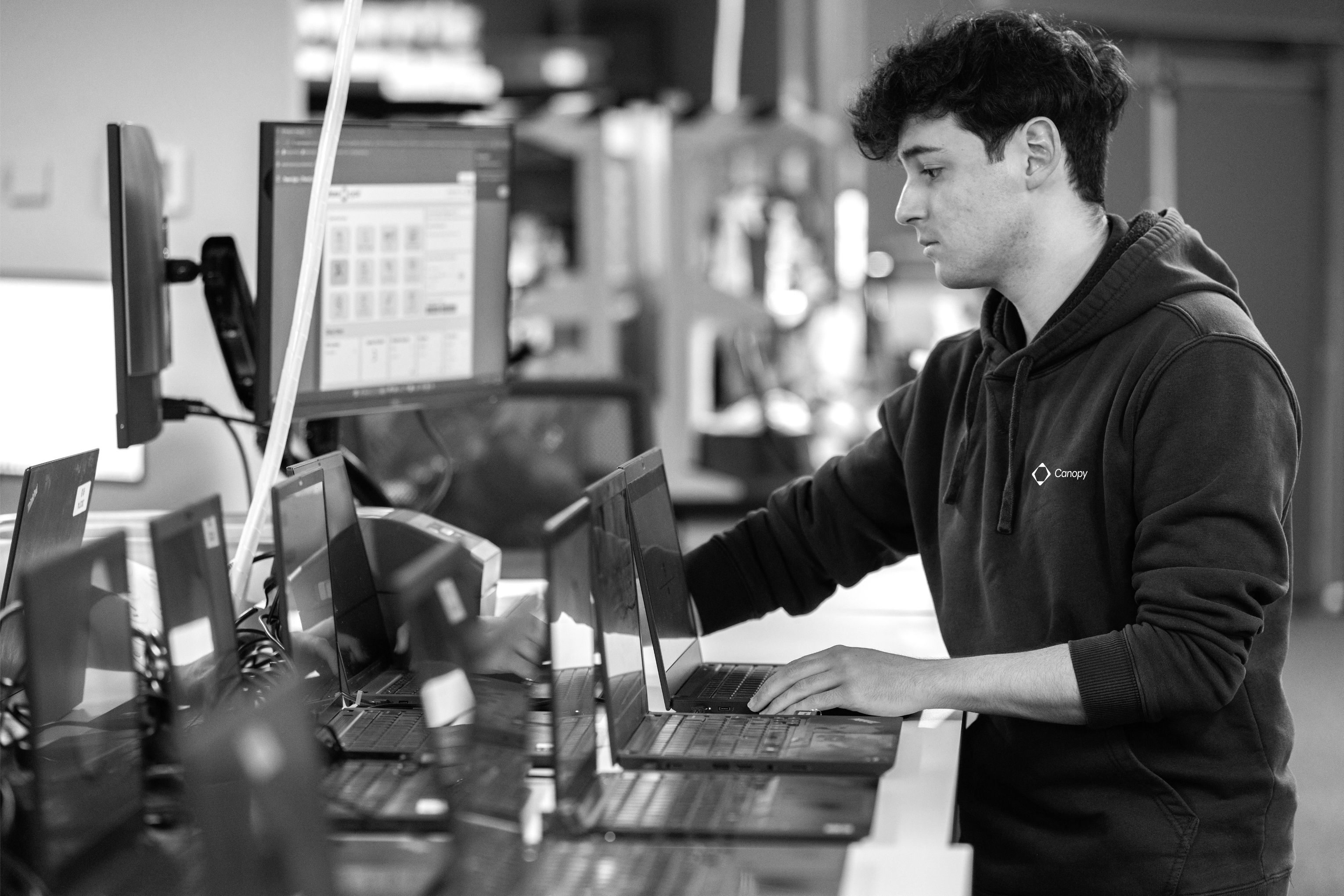 Canopy team member working with laptops at a device processing station.