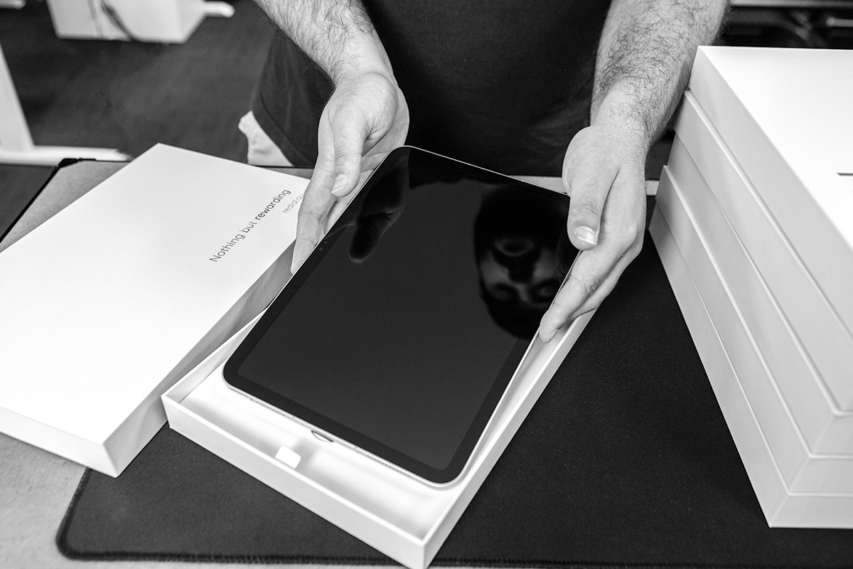 Canopy team member lifting an iPad from its box during processing.