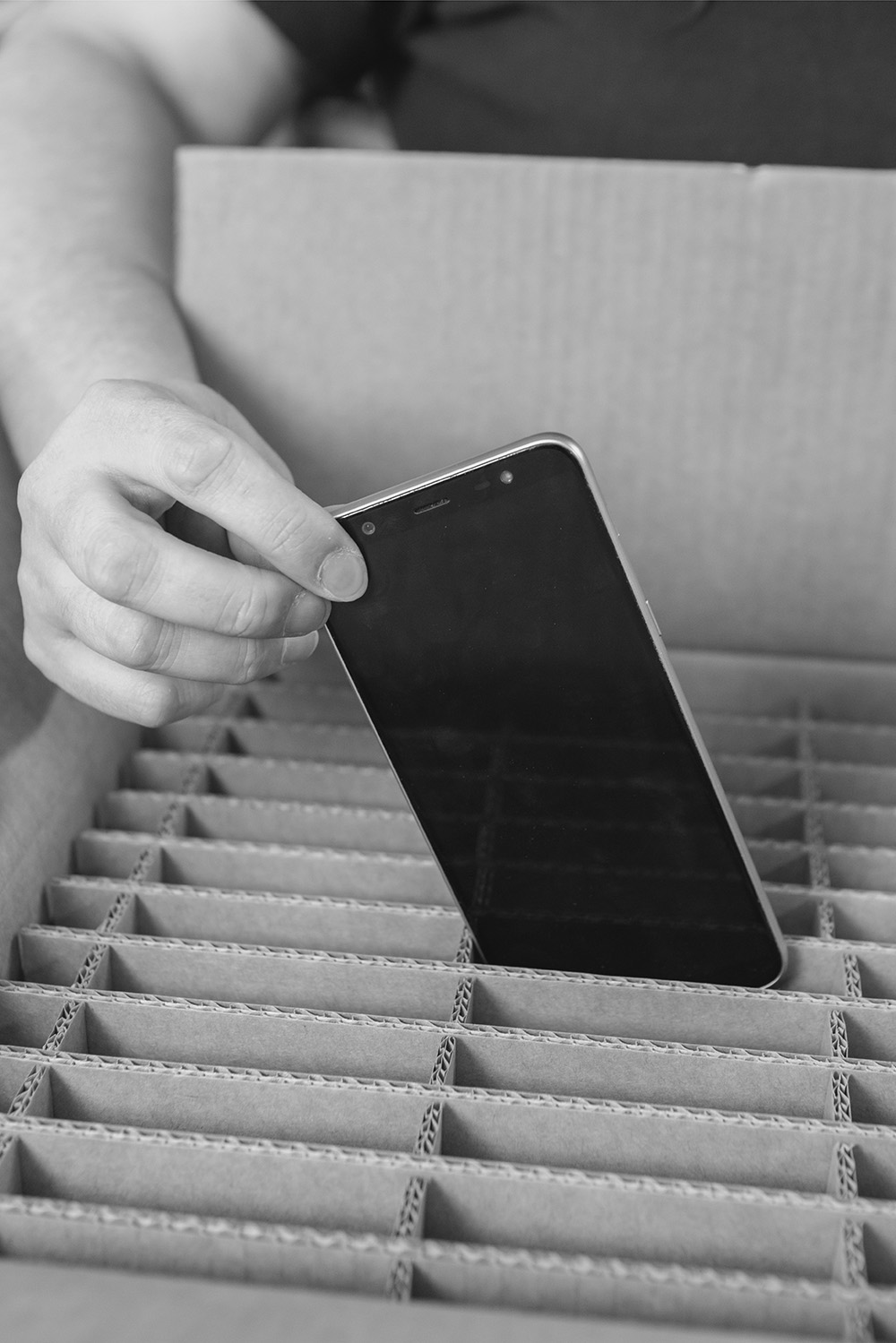 A returned smartphone being placed into a protective divider in a collection box.