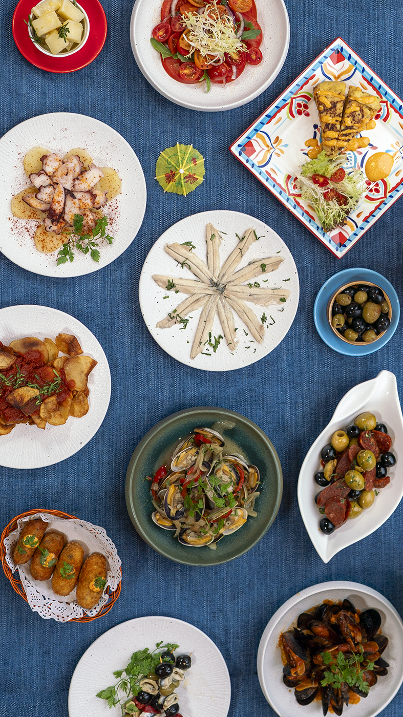 Selection of dishes including vegetarian paella, cold cuts and cheese board, casa 218 signature salade, patatas bravas