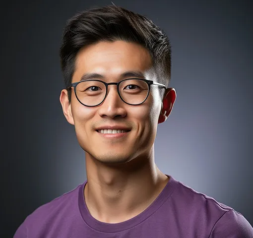 Smiling young Asian man with black hair and glasses wearing a purple crew neck shirt.