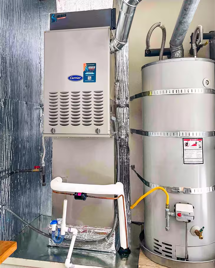 Indoor furnace unit next to a water heater with connected pipes and ventilation ducts.
