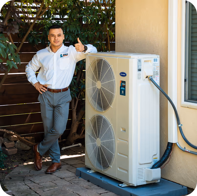 Technician in a white shirt giving thumbs up while standing next to a Carrier air conditioning unit outside a house.