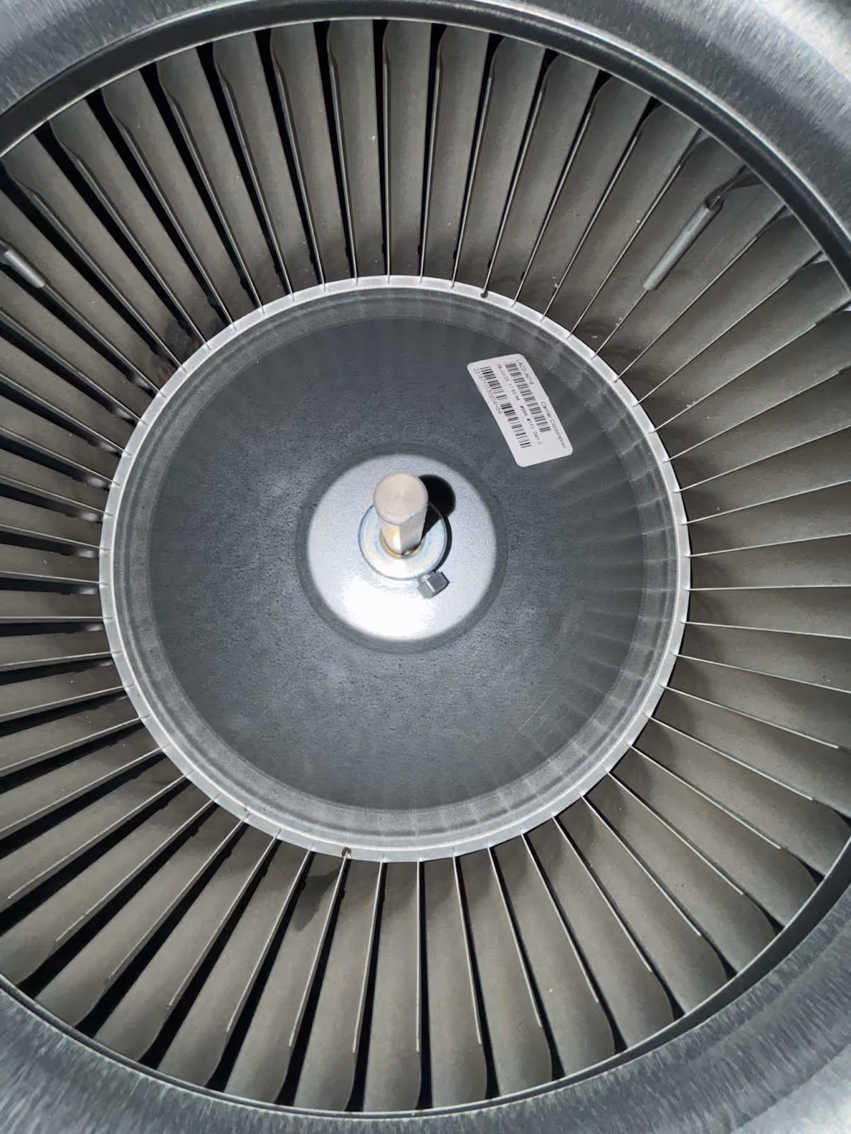 Close-up of a metallic turbine fan with multiple blades evenly spaced around a central hub.