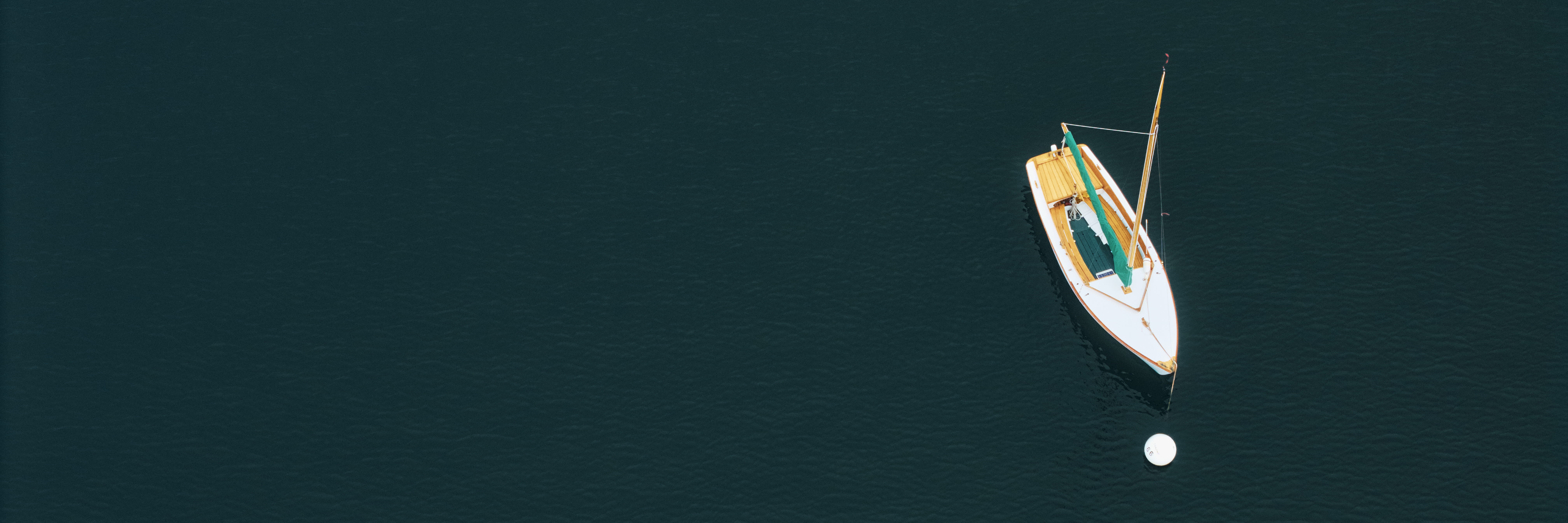 A single small boat on still, dark water in Rockport Harbor, Maine, seen from above