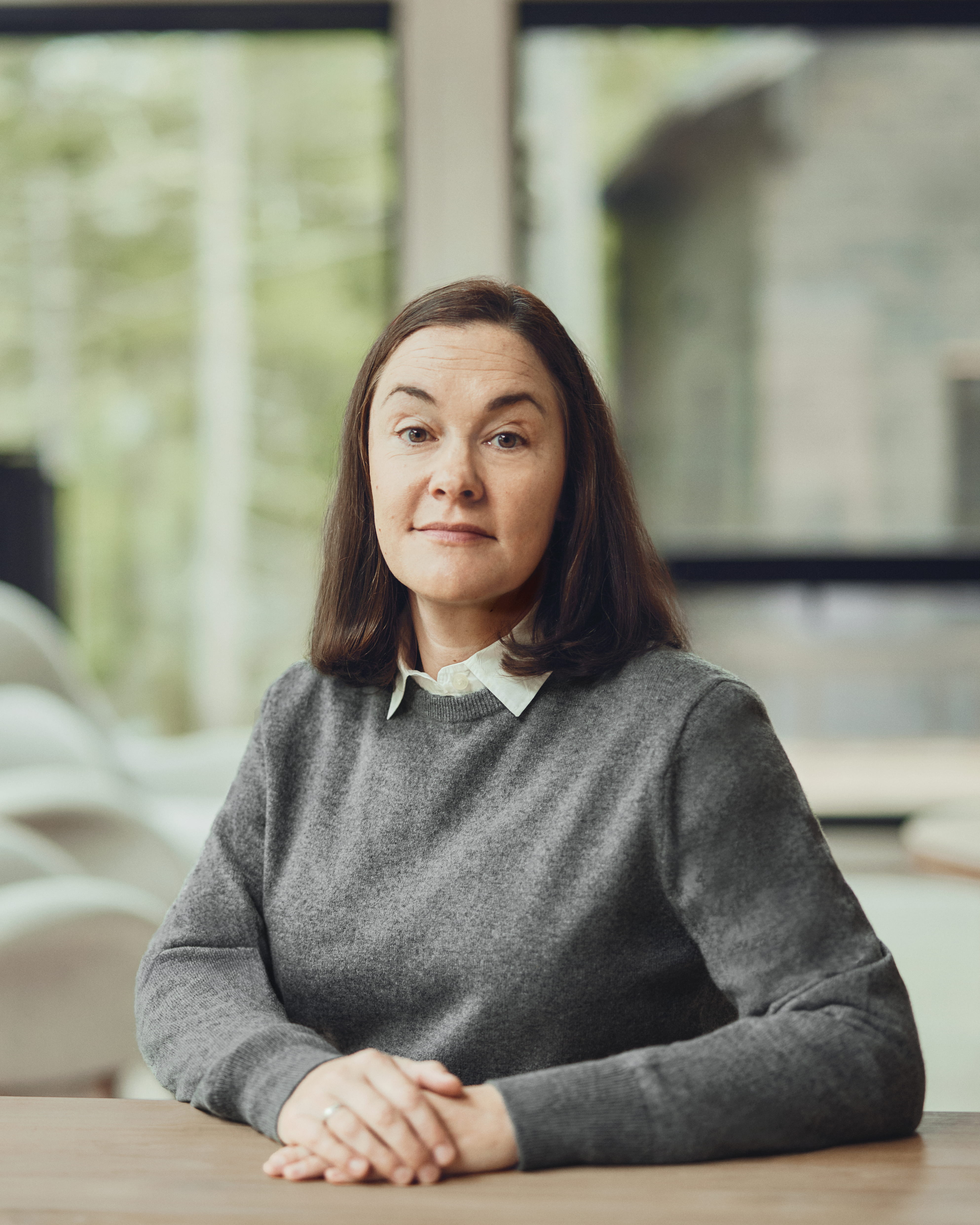 Brie Pio, founder and lead financial planner at Birch Point Wealth Management, seated at a wooden table with windows overlooking the woods