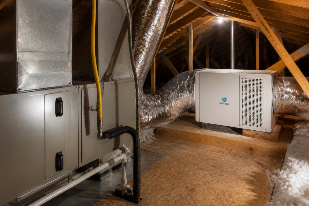 Interior view of an attic space showing professional HVAC equipment and a standalone air purification unit installed separately, both clean and well-organized with proper ventilation