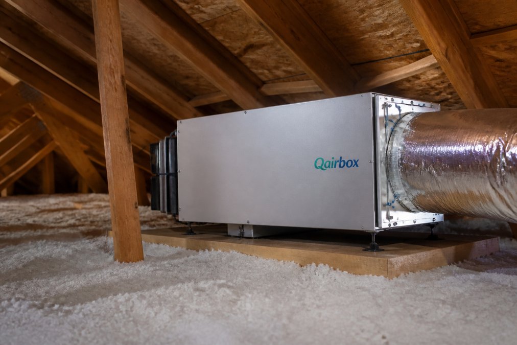 Interior view of an attic space with a modern air purification system installed, showing clean ductwork and the system mounted away from living areas