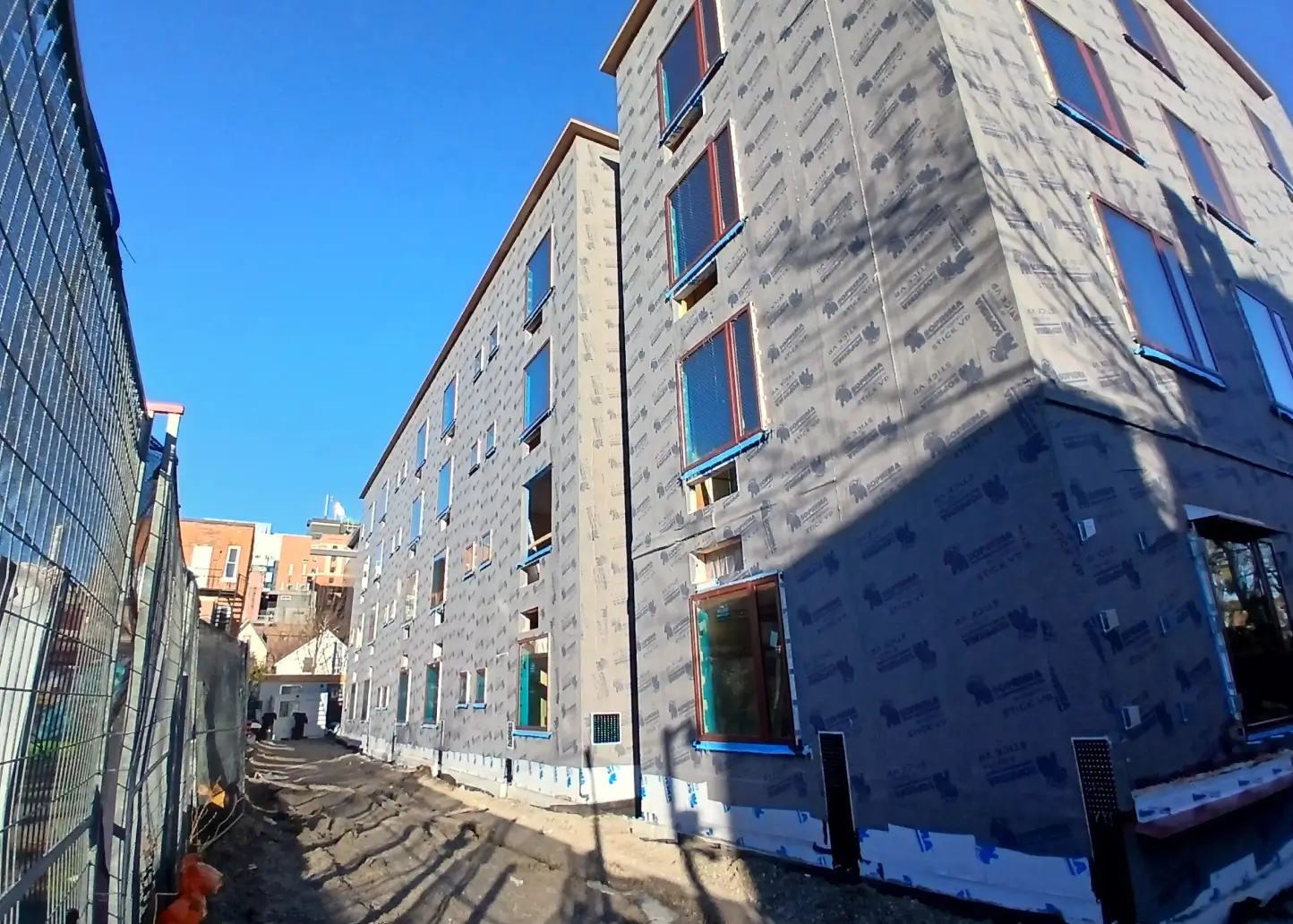 Multi-storey building wrapped in exterior air barrier membrane before cladding installation to improve energy efficiency and moisture control.