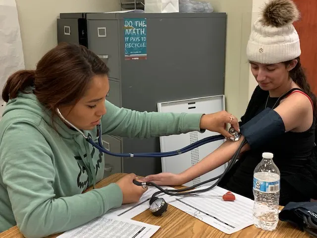 A student taking another student's blood pressure in a health sciences class