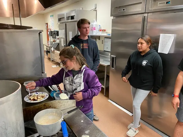 Students preparing and plating food in a commercial kitchen