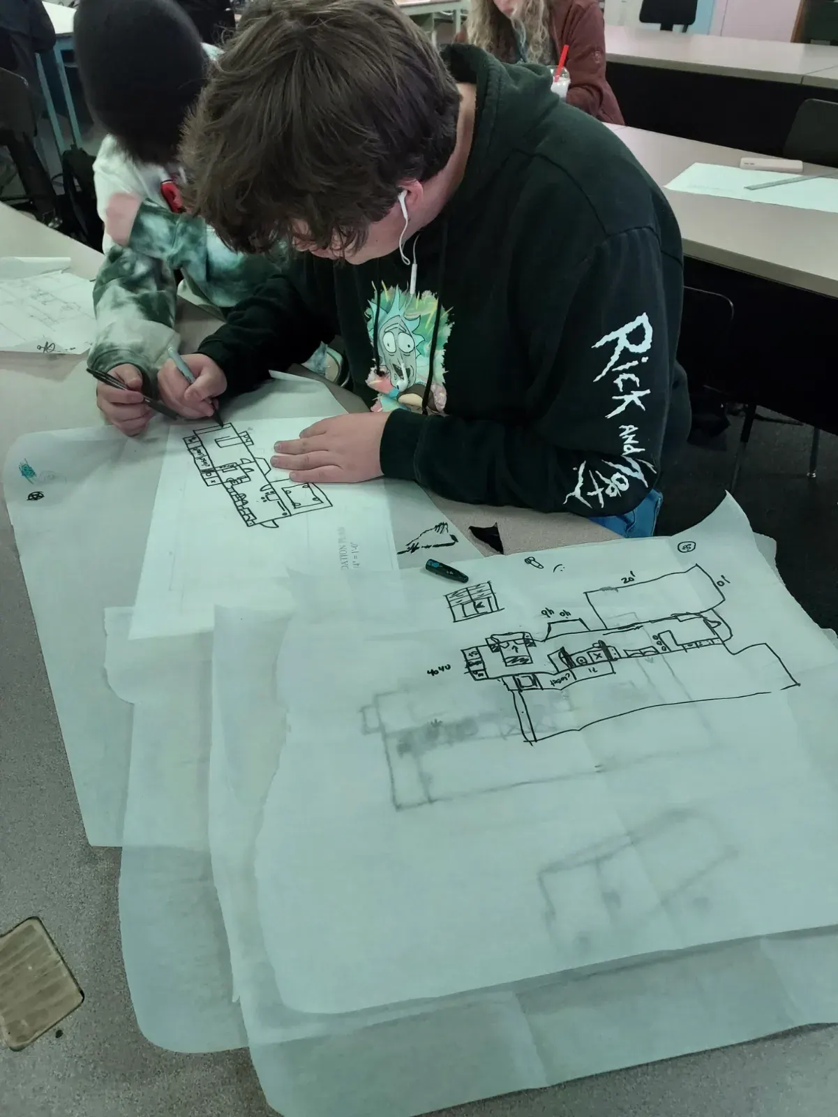 A student studying architectural drawings at a table