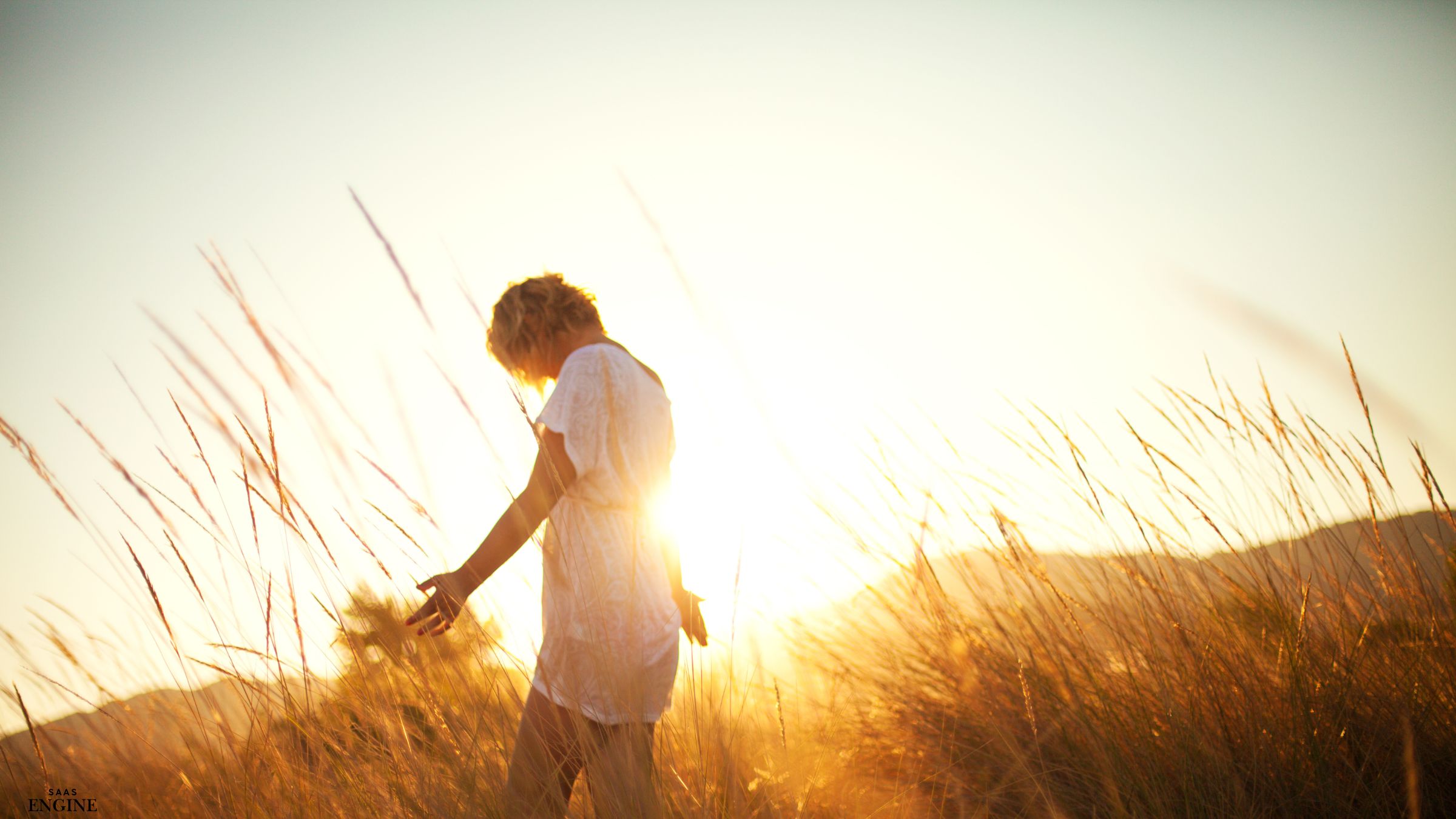 Woman touching wheat crops with her hand during golden hour