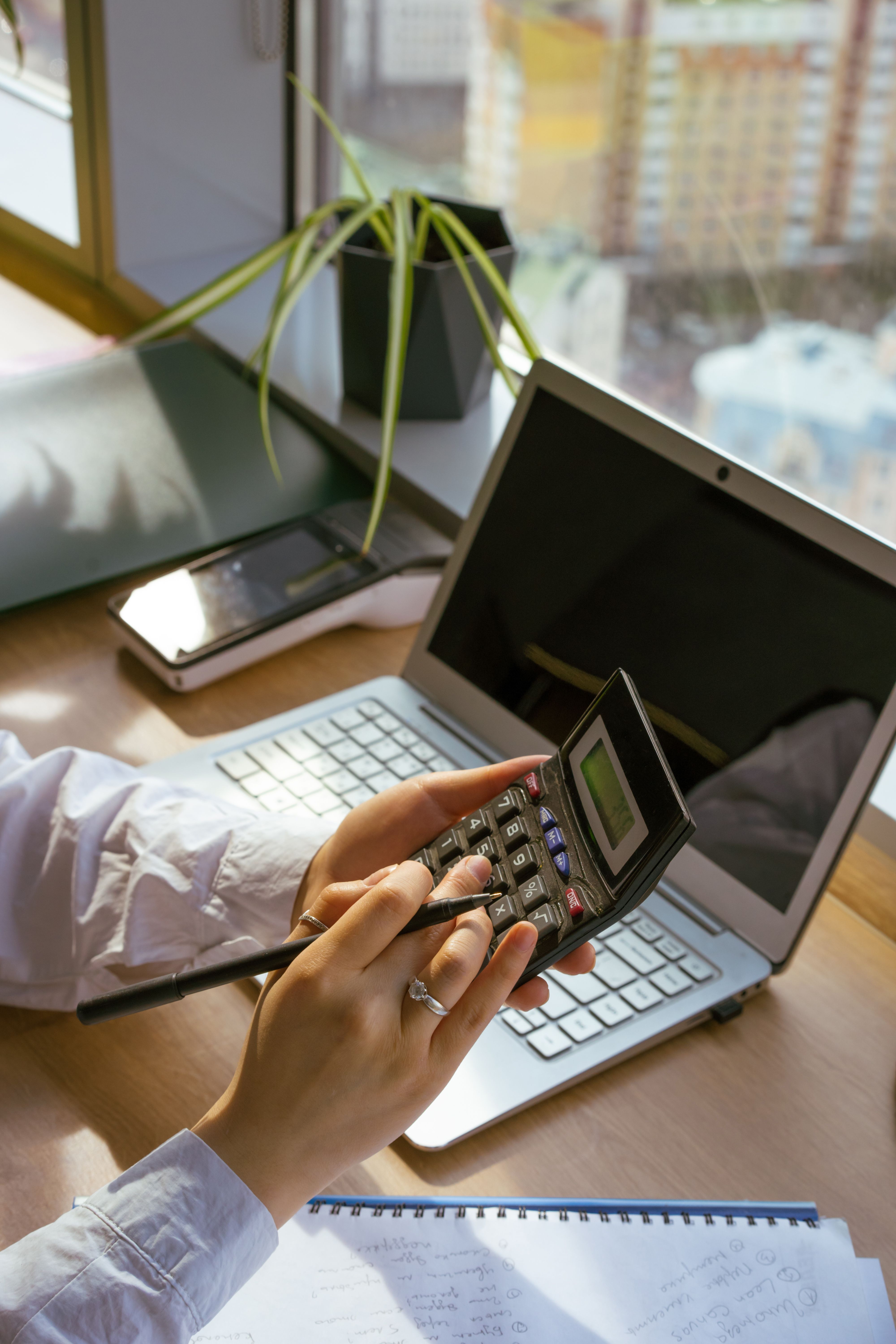 Marketing leader reviewing budget figures on a calculator and laptop at a desk